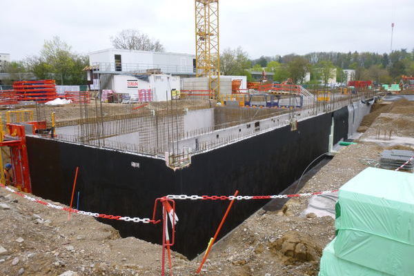 Kellerwand mit Baukran und Baucontainern